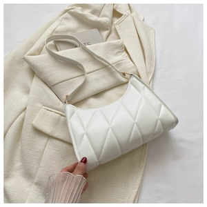 Detail of white quilted handbag featuring diamond embroidery and gold metal accents