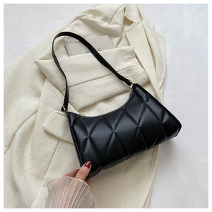 Detail of black quilted shoulder bag with diamond stitching on a beige blazer
