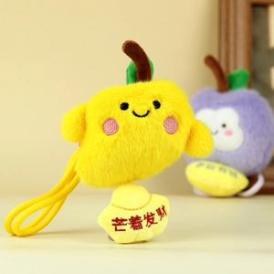 Dettaglio portachiavi a forma di mango in peluche con faccina e lingotto d'oro
