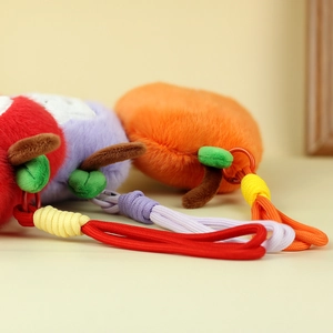 Dettaglio dei ciondoli a forma di frutta in peluche con corde intrecciate e tessuti