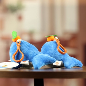 Detail view of blue orca plush keychains with orange accents on a dark wood surface