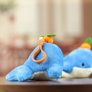Close-up of cute blue whale plush keychain with orange persimmon top and plastic clip