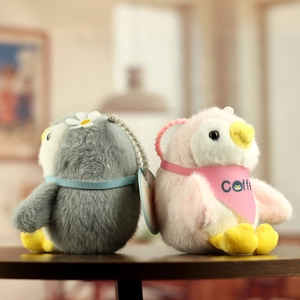 Close-up of cute plush penguin keychains in grey and pink with soft velvety textures