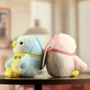 Close-up of cute pink and blue plush penguin keychains with soft textures and scarves