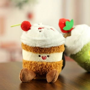 Détail macro du pendentif cupcake en peluche avec cerise et visage souriant brodé
