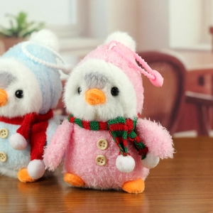 Détail de pingouins en peluche rose et bleu avec écharpes tricotées et boutons en bois