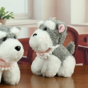 Détail d'un porte-clés peluche Schnauzer gris avec foulard rose sur table en bois