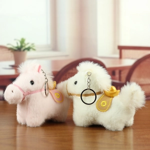 Detail of plush horse keychains in pink and white with gold ingot saddle accents
