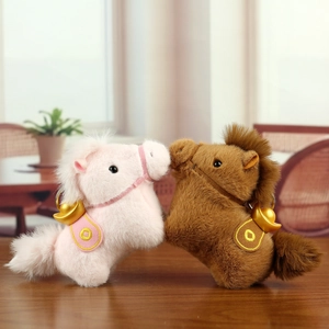 Detail of plush horse keychains in pink and brown with lucky golden ingots on back