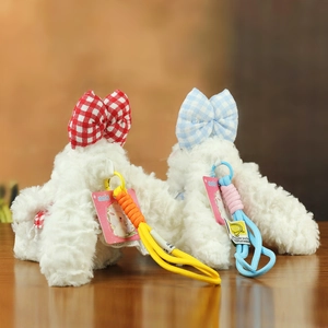 Détail de porte-clés lapins en peluche avec nœuds à carreaux et cordons tressés sur bois