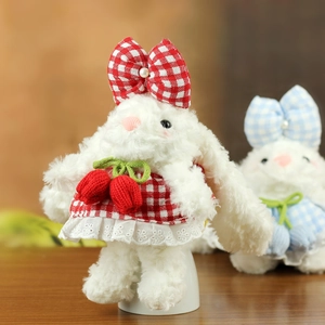 Gros plan d'un lapin en peluche en robe à carreaux rouges avec détails de tulipes tricotées