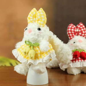 Détail d'un lapin en peluche blanche en robe à carreaux jaunes avec dentelle et tulipe