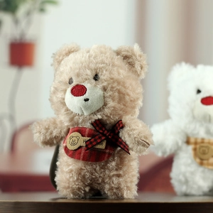 Detail of teddy bear plush with red nose, plaid scarf, and handmade wooden tag