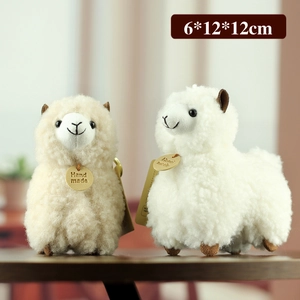 Cute beige and white alpaca plush keychains with handmade wooden tags in a warm home setting