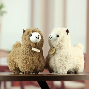 Close-up of soft alpaca plush keychain with handmade wooden tag and curly texture