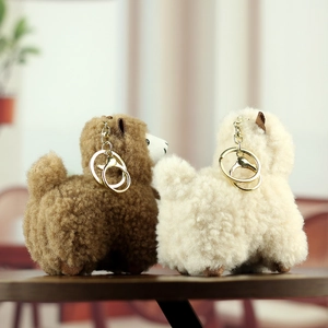 Close-up of soft alpaca plush keychains in brown and white with gold lobster clasps