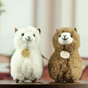 Close-up of white and brown plush alpaca keychains with handmade wooden tags