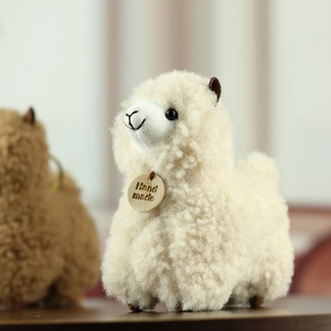 Detail of off-white plush alpaca keychain with curly fur and Hand Made leather tag