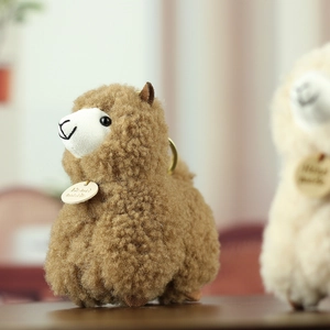 Close-up of brown alpaca plush keychain featuring curly fur and a handmade wooden tag