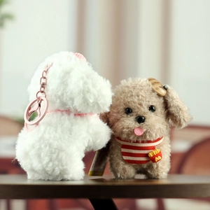 Close-up of plush puppy keychains in white and brown with cute scarf and accessories