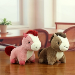 Porte-clés mignons chevaux en peluche rose et marron posés sur un bureau en bois