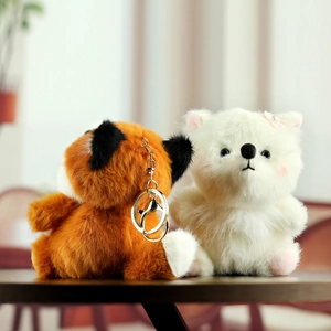 Détail de porte-clés renard et chat en peluche douce avec anneaux dorés sur table en bois