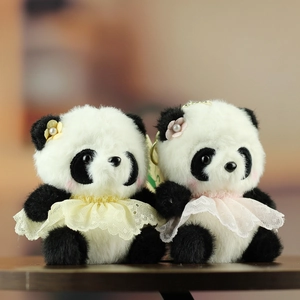 Dettaglio di portachiavi panda in peluche con gonne in pizzo e fiori su legno