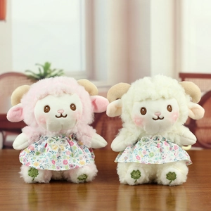 Close-up of cute plush sheep dolls in floral dresses with pearl bows and clover embroidery