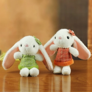 Gros plan de lapins en peluche en jupes de tweed et perles sur une surface en bois