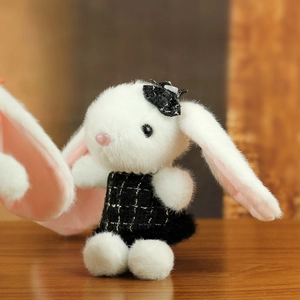 Détail d'un lapin en peluche blanc avec robe à carreaux et collier de perles fin