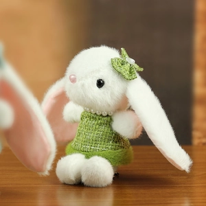 Détail d'un lapin en peluche blanc avec robe en tweed vert et collier de perles
