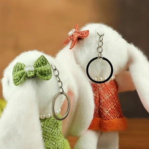 Gros plan de porte-clés lapin en peluche avec robes en tweed et colliers de perles