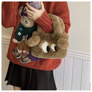 Détail d'un sac à main en peluche marron avec de grands yeux, porté par un mannequin