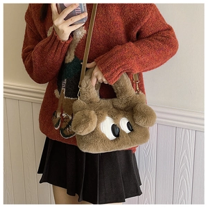 Détail du sac chiot en peluche marron avec grands yeux porté par un mannequin en pull