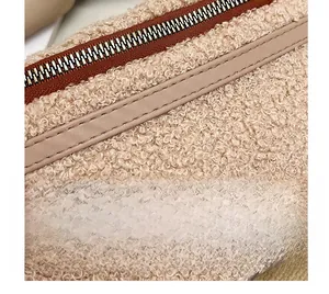 Close-up of beige faux shearling fanny pack with brown leather trim and metal zipper