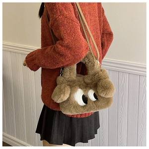 Détail d'un sac en peluche marron avec motif yeux de dessin animé et bandoulière