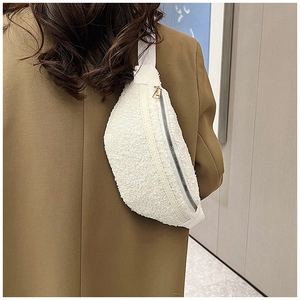 Detail of white plush belt bag showing soft faux shearling texture and gold zipper