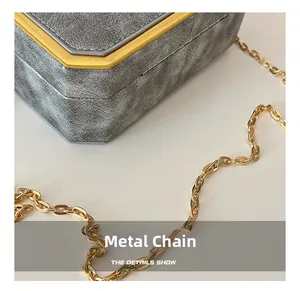 Detailed close-up of hardware chain and gold octagonal metal edge on grey textured box bag