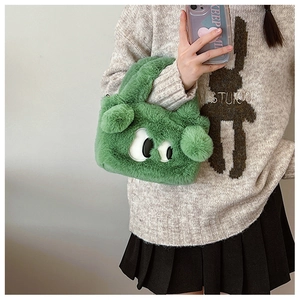 Détail du sac à main en peluche verte à yeux de dessin animé porté par un mannequin