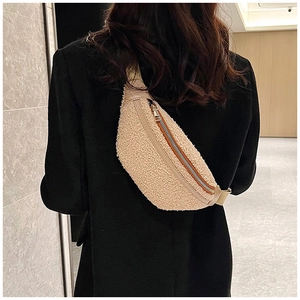 Close-up of beige faux shearling fanny pack worn crossbody over a black blazer jacket