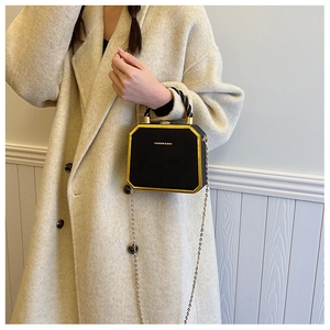 Side view of a vintage black octagonal chain bag worn with a white wool coat