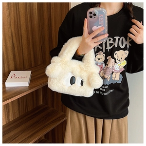 Détail de la texture d'un sac à main en peluche blanc crème avec broderie de grands yeux