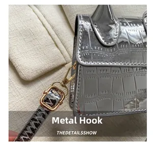 Detailed macro of silver croc-embossed mini bag with premium gold metal hooks