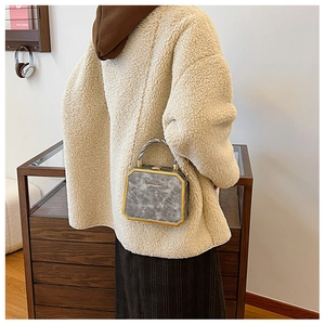 Detail of mini square marble box bag with gold metal frame and chain strap on model