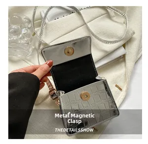 Close-up of silver mini crossbody bag showing metallic magnetic buckle and croc texture
