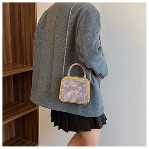 Detail of purple marble pattern box bag with gold chain strap on a model shoulder