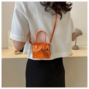 Close-up of orange croc-embossed mini bag with metallic finish shown on a model
