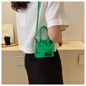 Detailed macro view of the glossy green crocodile pattern on this mini crossbody handbag