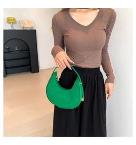 Detailed view of a bright green felt hobo bag held by a model in a modern interior