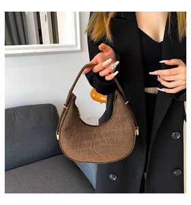 Detail of dark brown croco-embossed crescent bag with gold-tone hardware and zippers